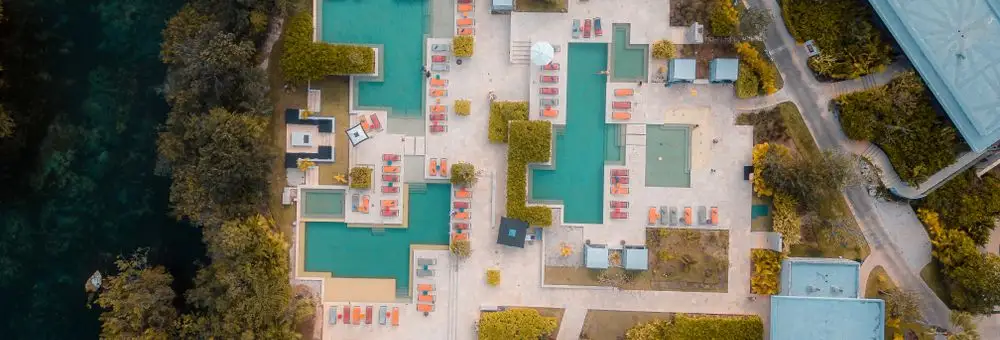 A resort seen from directly above, its pools and terraces laid out beside the shore