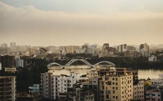 The Dhaka skyline at sunset, with a bridge crossing the river
